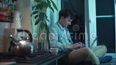 一个年轻人用电脑坐在厨房里<strong>烧水壶</strong>